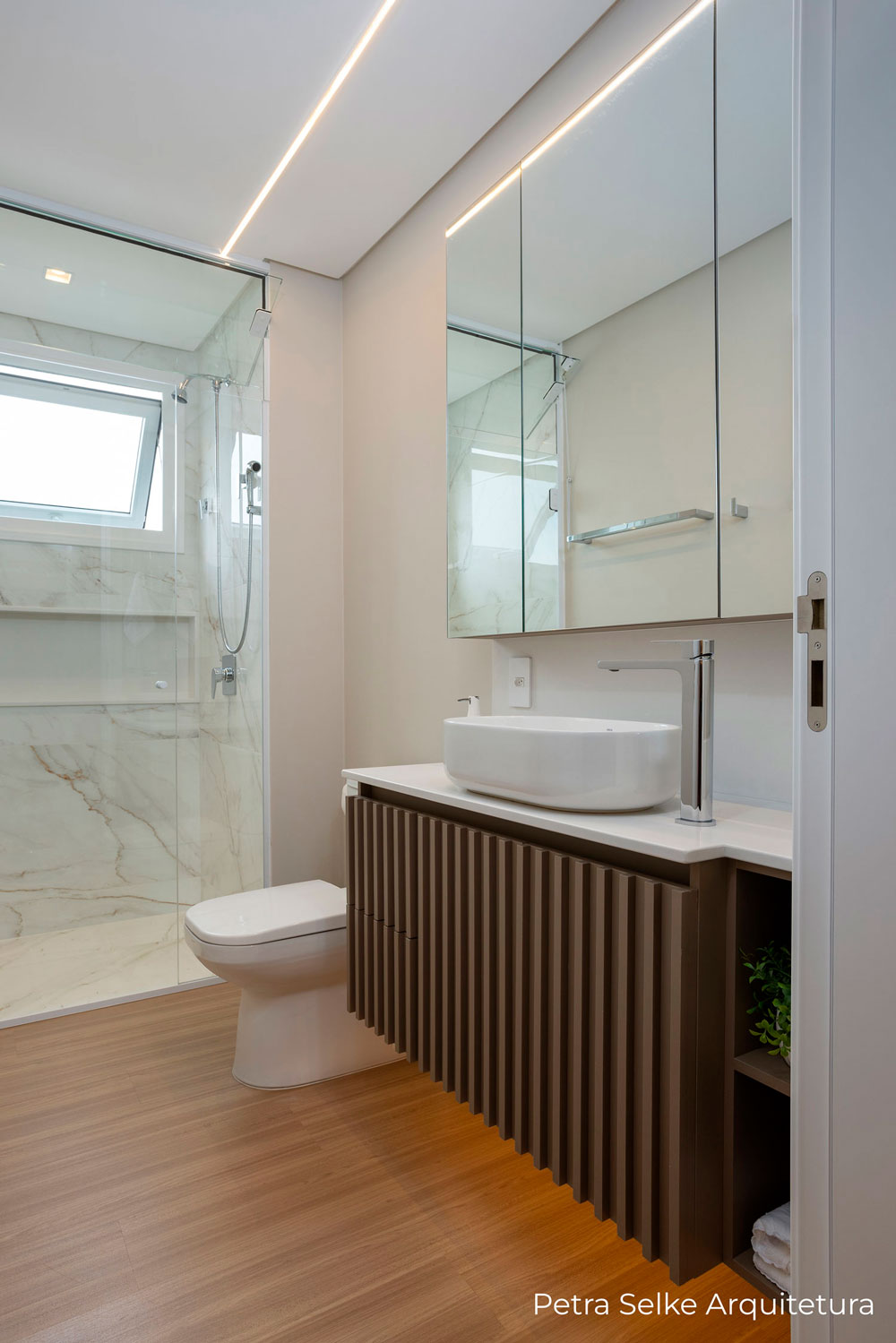 Banheiro aéreo com espelho e móvel com portas ripadas em MDF marrom